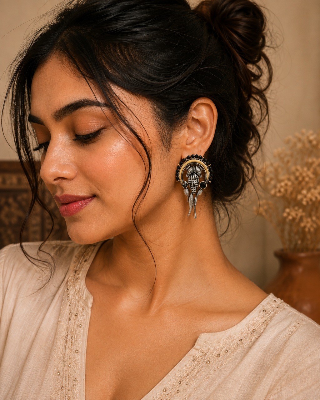 A woman wearing a large, ornate gold and black fish-shaped earring, shown in a close-up portrait against a warm, neutral background.