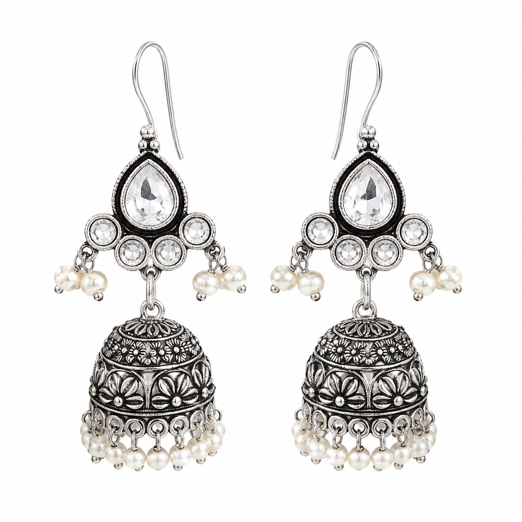 A pair of silver-toned jhumka earrings with clear teardrop stones, small white pearl beads, and intricate filigree detailing, shown on a plain white background.