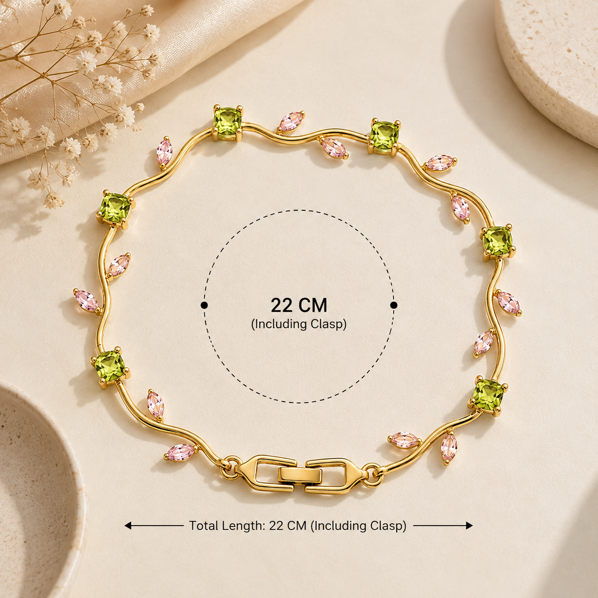 Gold bracelet with green square gemstones and pink marquise gemstones, shown on a beige surface with measurement callouts indicating a total length of 22 cm including clasp.